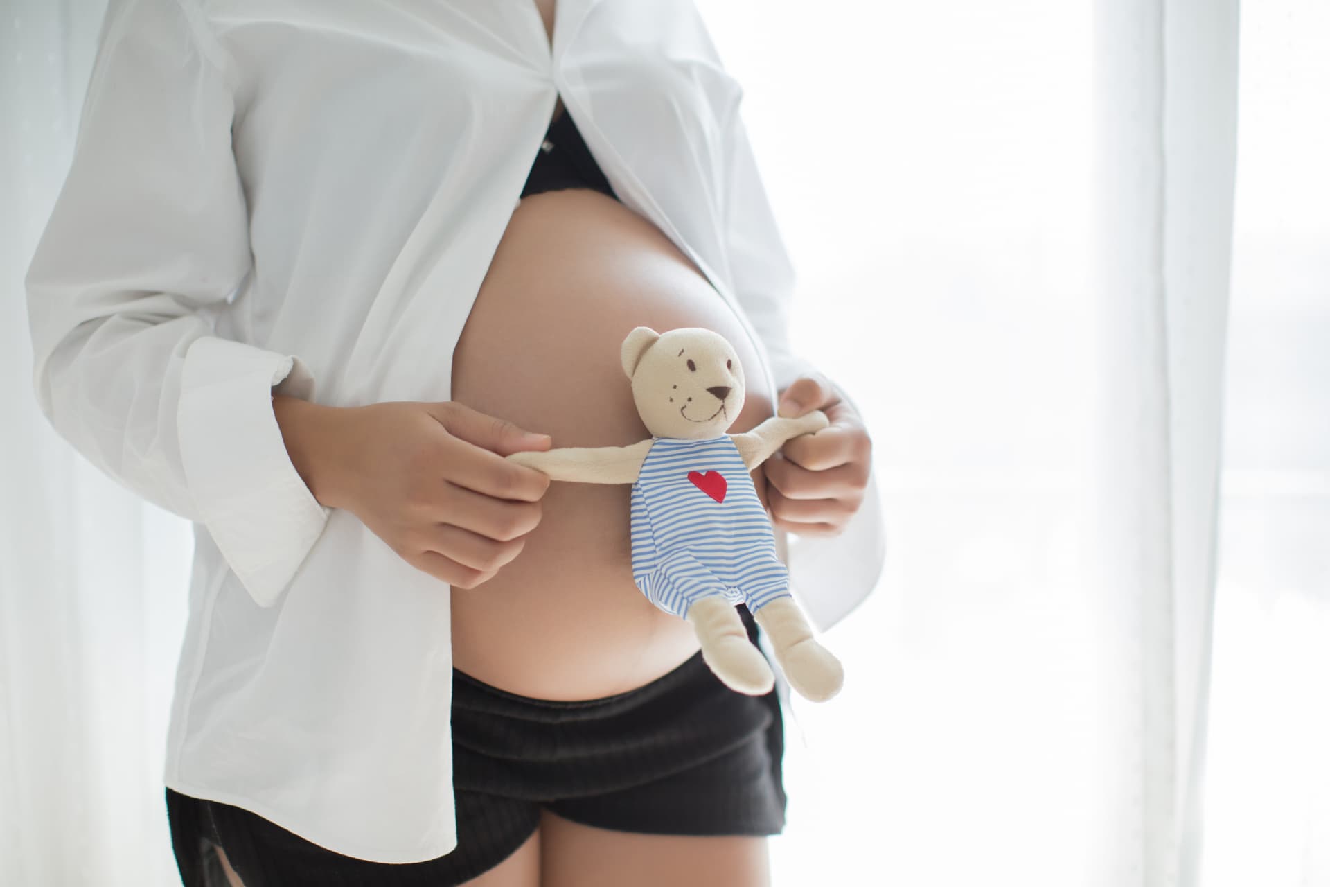 Gestante segurando um ursinho de pelúcia junto à barriga